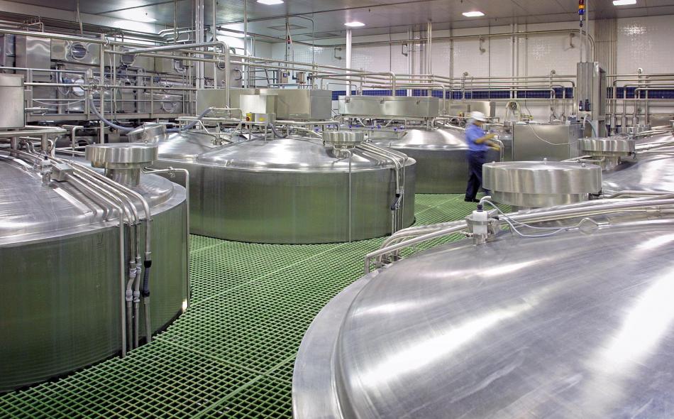 inspector walking past food storage tanks.